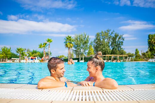 Lächelndes Paar im Außenpool des Campingplatzes CAPFUN Tordera-Nacions in Malgrat de Mar.