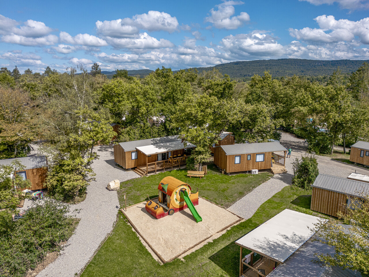 Playground and wooden Mobile homes, aerial view at camping CLICOCHIC Trelachaume in Maisod (39).