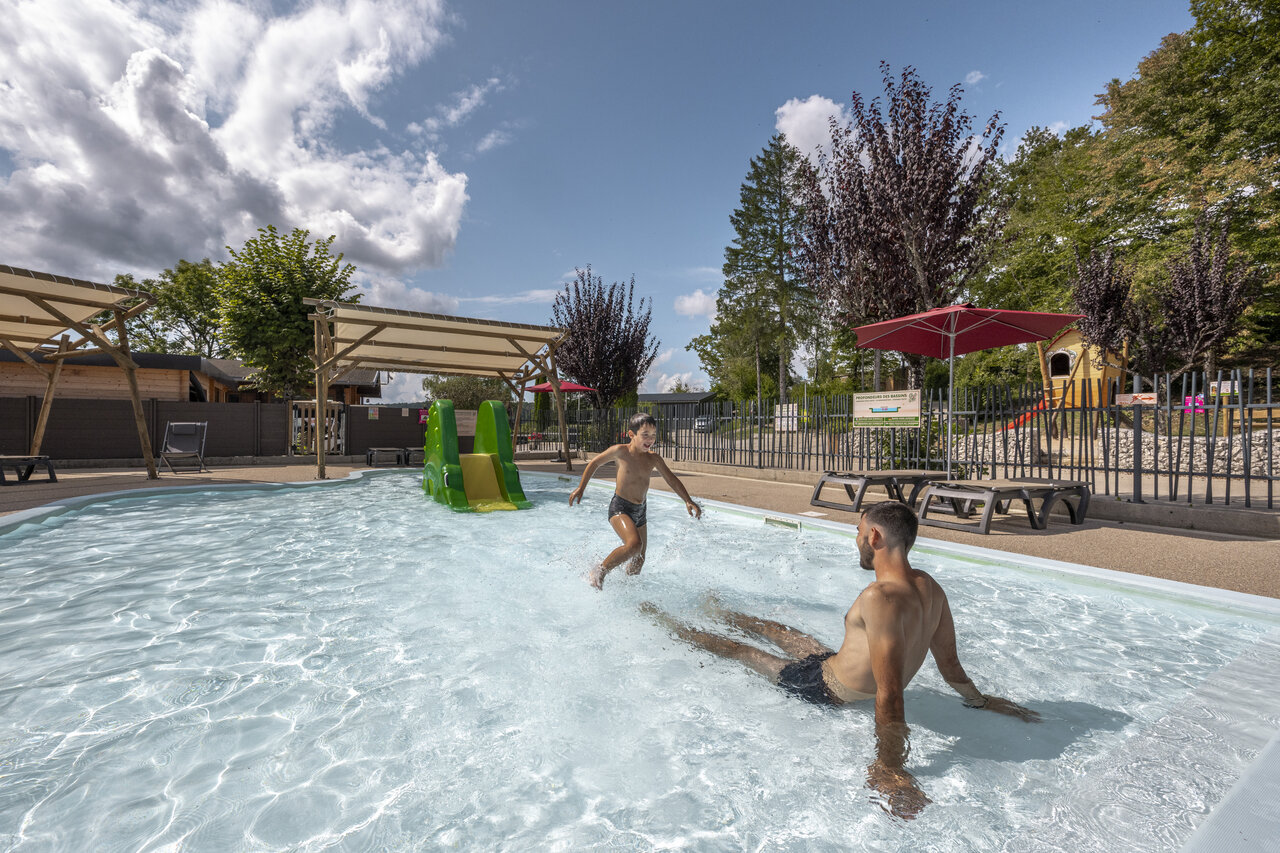 Outdoor swimming pool with slide and children playing at CLICOCHIC Trelachaume campsite in Maisod (39).