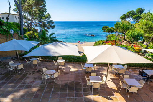 Restaurantterrasse, Tische, Sonnenschirme, Meer auf dem Campingplatz CAPFUN Treumal in Platja d'Aro.