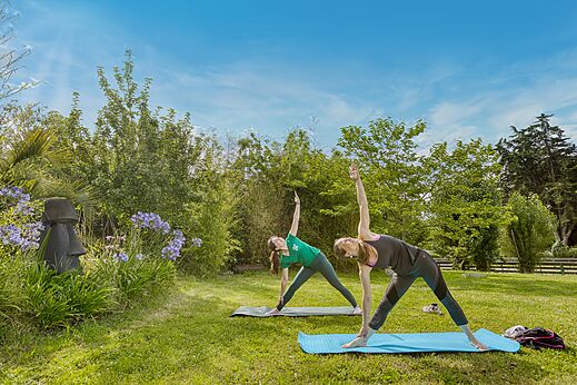 Zwei Frauen praktizieren Yoga im Freien auf dem Campingplatz CLICOCHIC Trois Chênes.