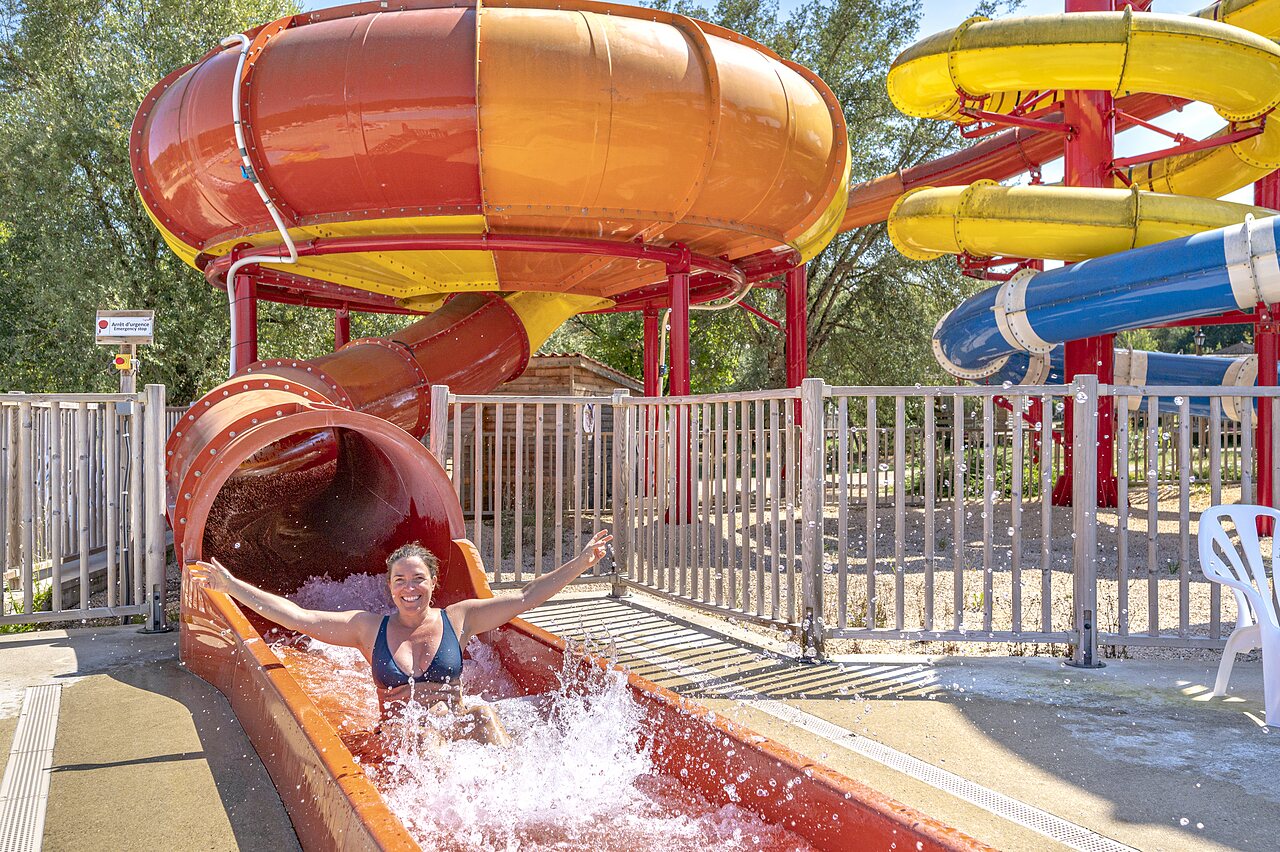 Smiling woman descending a large water slide at CAPFUN Ullule campsite in Tournon d'Agenais (47).