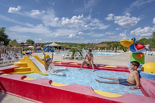 Kinder spielen im Wasserspielbereich mit Rutsche auf dem Campingplatz CAPFUN Ullule in Tournon d'Agenais (47).