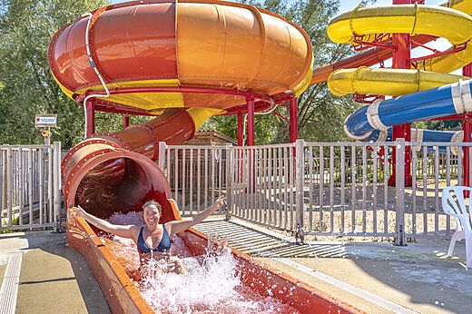 Lächelnde Frau rutscht eine riesige Wasserrutsche hinunter auf dem Campingplatz CAPFUN Ullule in Tournon d'Agenais (47).
