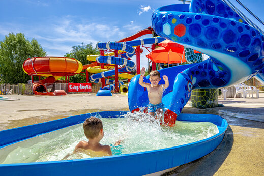 Kinder spielen im Planschbecken mit bunten Rutschen auf CAPFUN Ullule, Tournon d'Agenais.