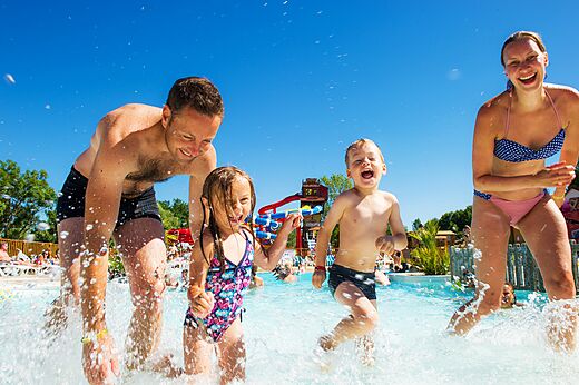L�chelnde Familie spielt im Wellenbad mit Rutschen auf Camping CAPFUN Ullule in Tournon d'Agenais (47).