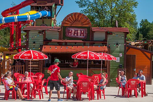 Au�enbar, rote Tische, Sonnenschirme und Rutschen auf Camping CAPFUN Ullule.