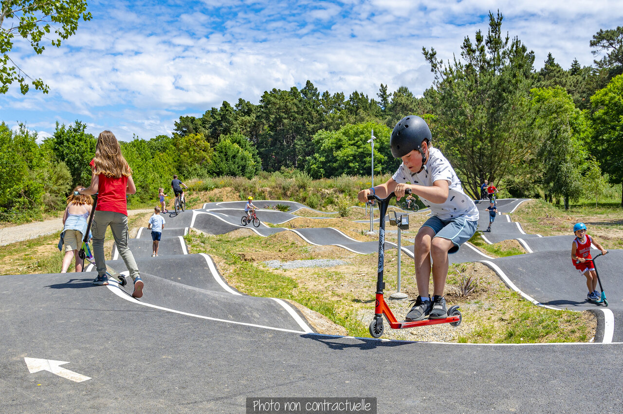 Pump track with children on scooters and bikes at CAPFUN Val d'Authie campsite.