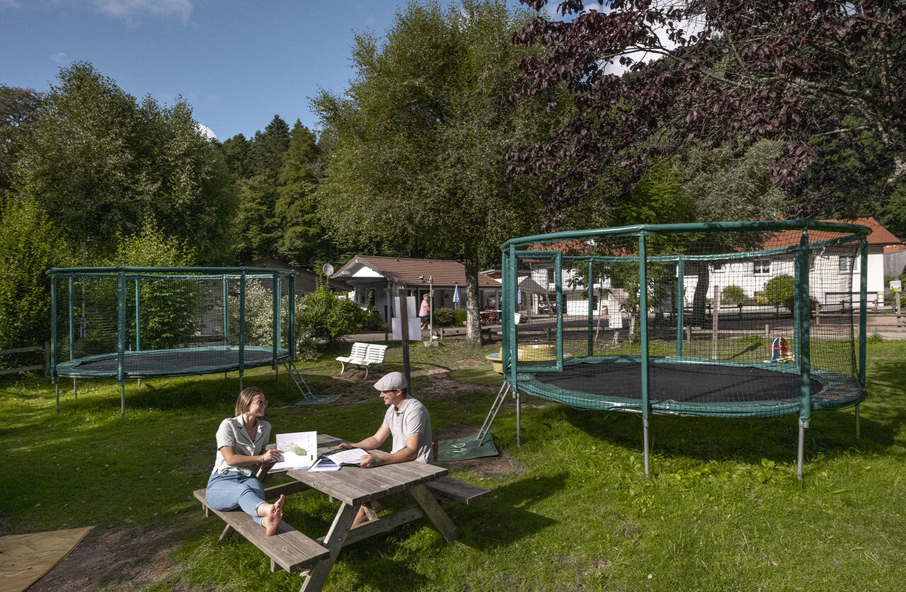 Deux trampolines et couple � table pique-nique au camping CLICOCHIC Verte Vall�e � XONRUPT LONGEMER.