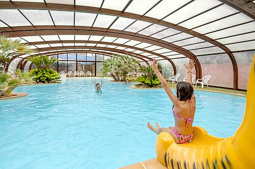 Überdachtes Schwimmbad mit Rutsche und Kindern auf dem Campingplatz CAPFUN Vignes d'Or in Serignan