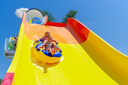 Zwei Kinder auf Reifen rutschen riesige Wasserrutsche auf Camping CAPFUN Vignes d'Or in Serignan.