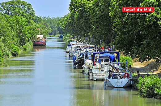 Historischer Canal du Midi mit festgemachten Booten und grünen Bäumen in Okzitanien.