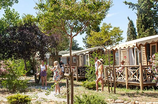 Holz-Mobilheime mit Terrassen und Personen beim Badmintonspielen auf dem Campingplatz CAPFUN Vignes d'Or in Serignan.