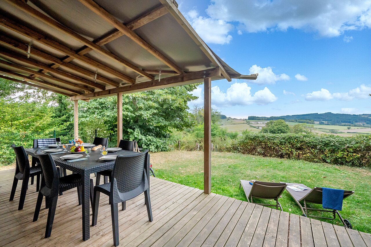 Terraza cubierta, mesa de comedor, vista natural en el camping CLICOCHIC Village des Meuniers en Dompierre-les-Ormes (71).