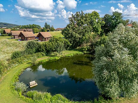 Houten stacaravans en vijver bij CLICOCHIC Village des Meuniers in Dompierre-les-Ormes.