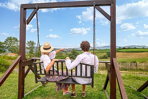 Koppel op schommel genietend van panoramisch uitzicht op natuur op camping CLICOCHIC Village des Meuniers in Dompierre-les-Ormes (71).