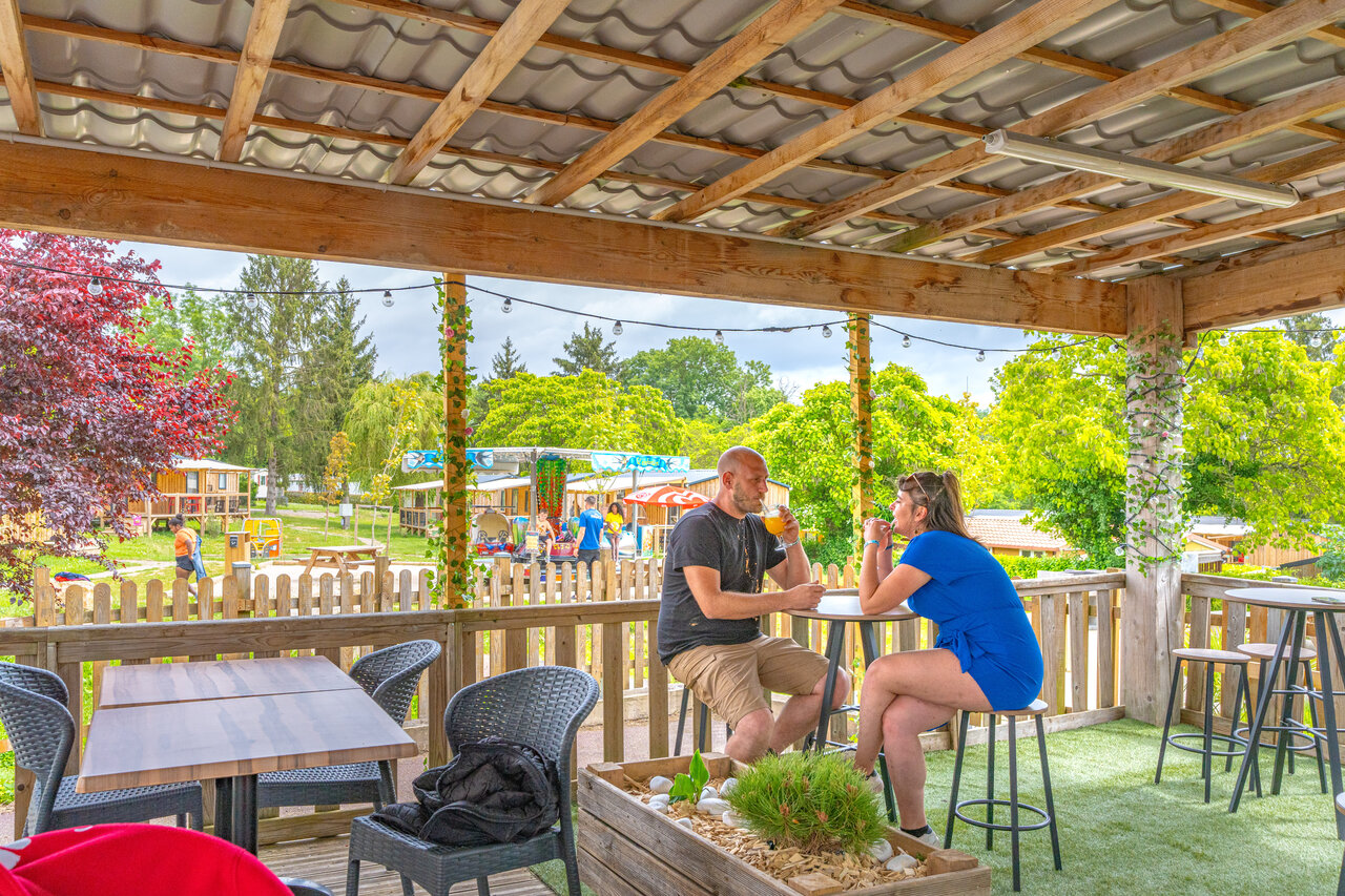 Belebte Barterrasse, Paar und Spielplatz auf dem Campingplatz CAPFUN Le Village Parisien in VARREDDES (77).