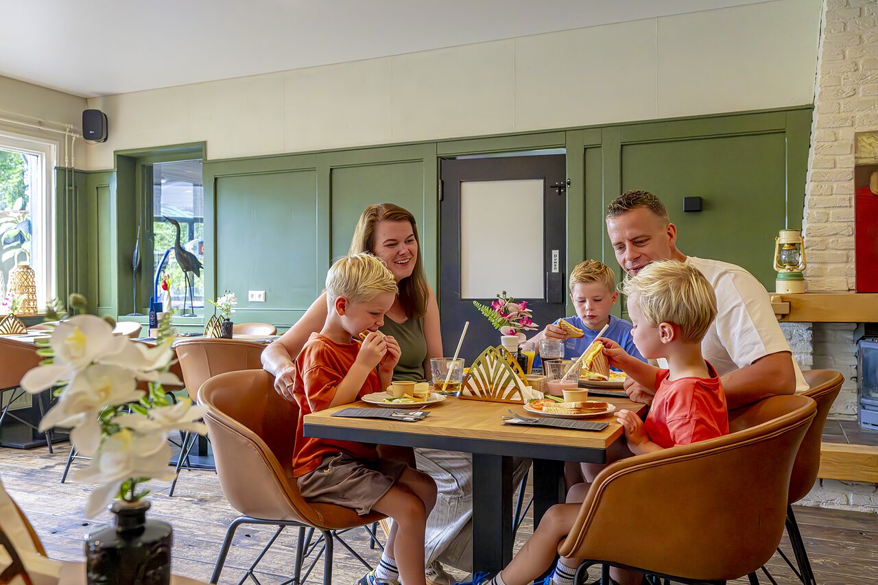 Familie isst im Restaurant des Campingplatzes CAPFUN Vlinderloo in Enschede.