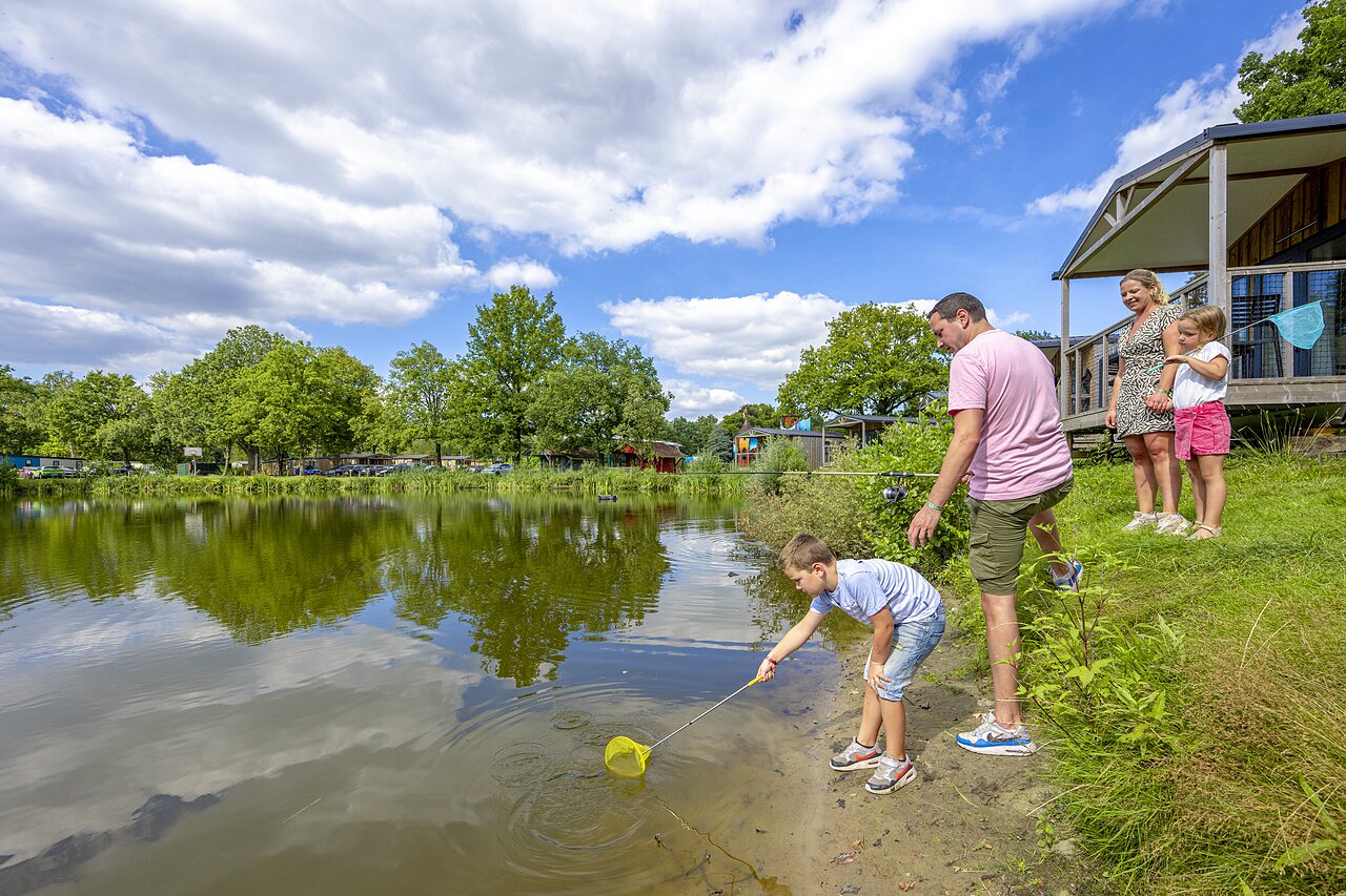 Kind fischt mit Kescher am See des Campingplatzes CAPFUN Vlinderloo in Enschede.