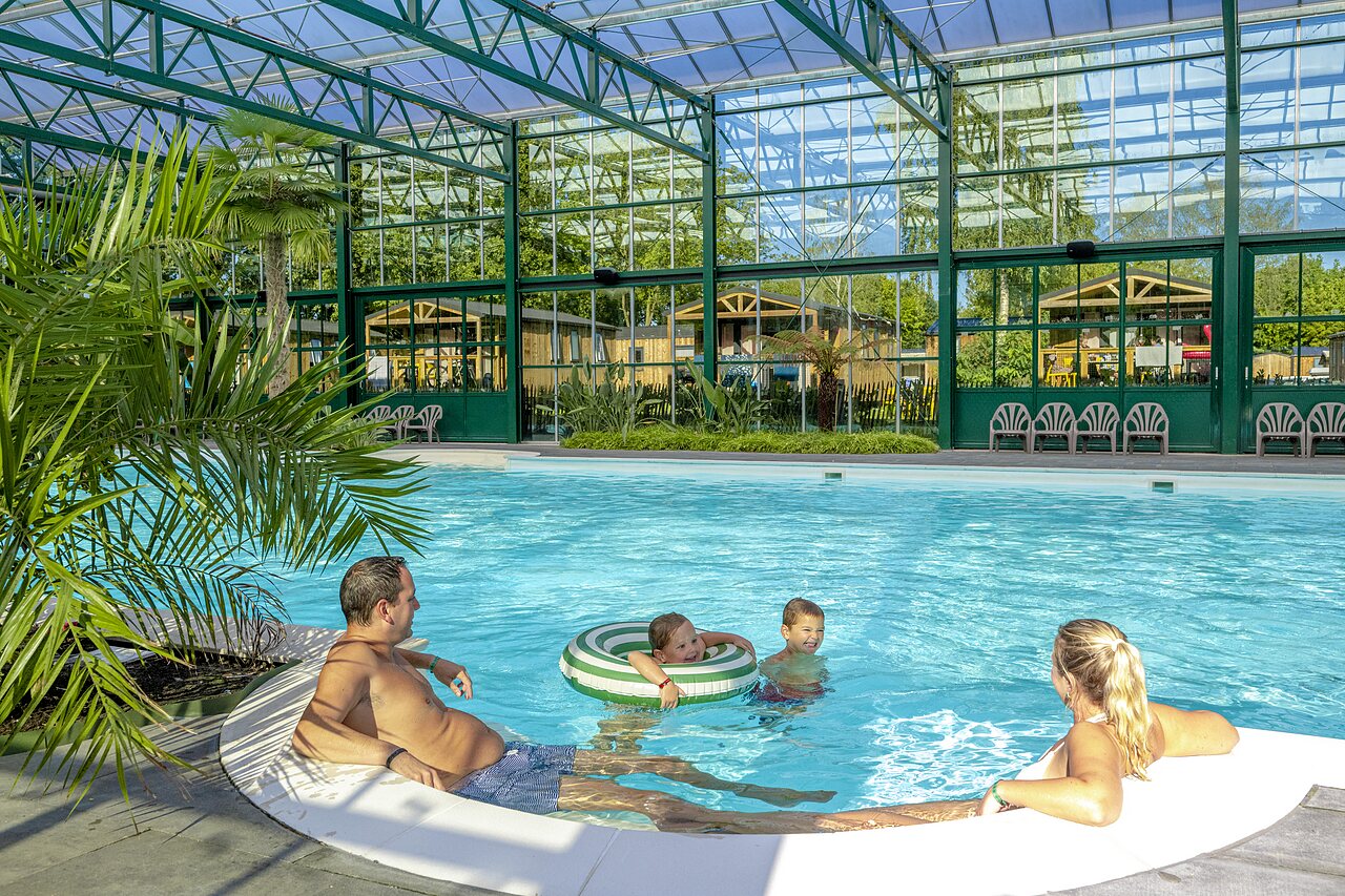 Familie genie�t das �berdachte Schwimmbad mit Mobilheimen auf dem Campingplatz CAPFUN Vlinderloo in Enschede.