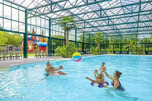 Piscine couverte avec famille jouant au ballon au camping CAPFUN Vlinderloo à Enschede.