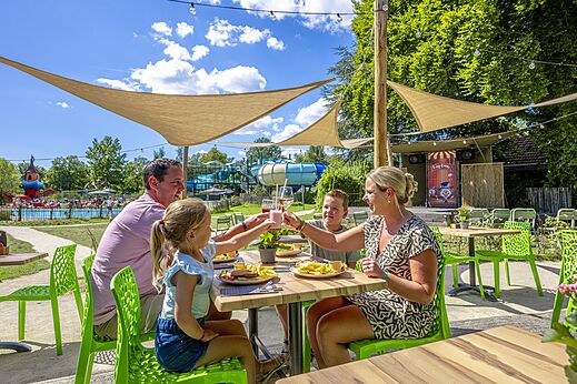 Familie luncht op het terras van het restaurant op camping CAPFUN Vlinderloo in Enschede.