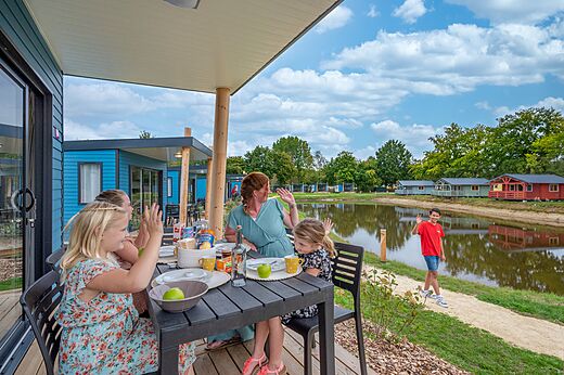 Familie op terras van stacaravan aan meer op camping CAPFUN Vlinderloo.