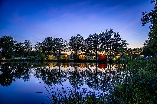 Verlichte stacaravans aan het meer op camping CAPFUN Vlinderloo in Enschede.