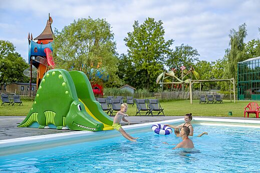 Kind auf Krokodilrutsche im Au�enpool auf dem Campingplatz CAPFUN Vlinderloo in Enschede.
