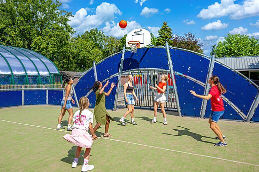 Jugendliche spielen Basketball auf einem Multisportplatz auf dem Campingplatz CAPFUN De Waldsang in Bakkeveen.