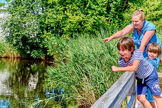 Familie beobachtet Natur am Wasser auf dem Campingplatz CAPFUN De Waldsang.