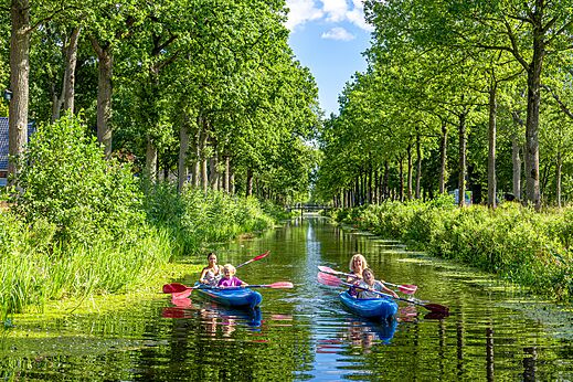 Familien im Kajak auf einem grünen Kanal auf dem Campingplatz CAPFUN De Waldsang in Bakkeveen.