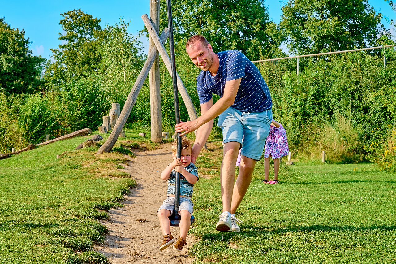 Vater und Kind an Seilrutsche auf dem Spielplatz im Camping CAPFUN Wieskamp in Winterswijk Henxel.