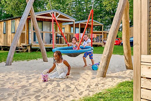 Schaukel, Sand und spielende Kinder auf Campingplatz CAPFUN Wieskamp in Winterswijk Henxel.