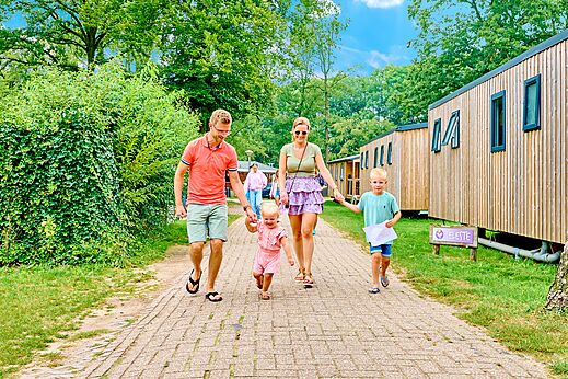 Familie spaziert vor modernen Mobilheimen auf dem Campingplatz CAPFUN Wieskamp in Winterswijk Henxel.