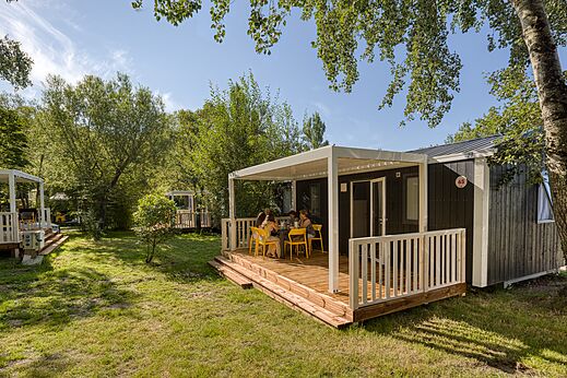 Modernes Mobilheim mit überdachter Terrasse und Familie auf Camping CAPFUN het Winkel in Winterswijk.