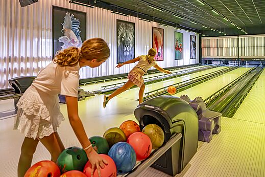 Kinder spielen Bowling in der Spielhalle des Campingplatzes CAPFUN het Winkel.