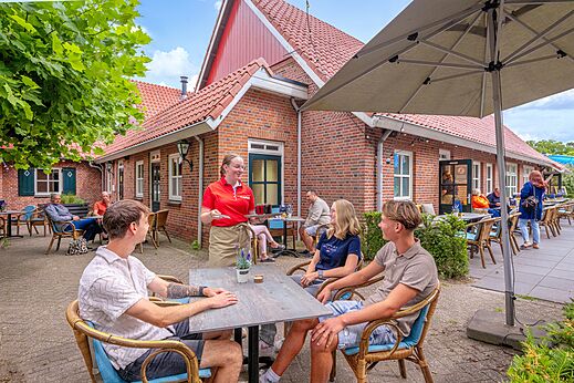 Außenterrasse des Restaurants mit Kellnerin und Gästen auf dem Campingplatz CAPFUN het Winkel in Winterswijk.