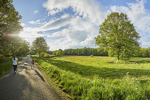 Grüner Weg mit Kind auf Roller und Erwachsenem, CAPFUN het Winkel in Winterswijk.
