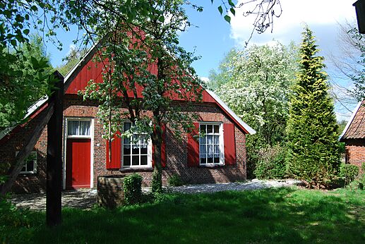 Traditionelles Backsteinhaus, rote Fensterläden, blühender Garten auf dem Campingplatz CAPFUN het Winkel in Winterswijk.