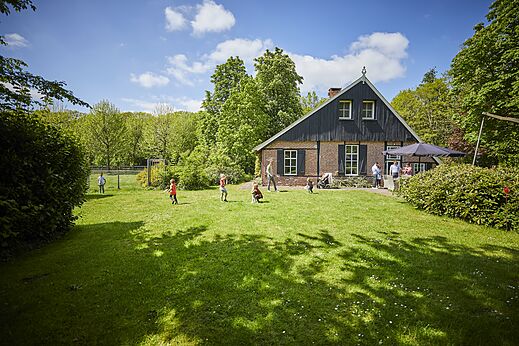 Restaurant mit Außenterrasse und spielenden Kindern auf dem Rasen auf dem Campingplatz CAPFUN het Winkel in Winterswijk.