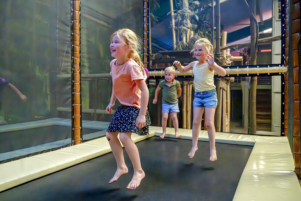 Lachende Kinder springen auf Indoor-Trampolinen auf dem Campingplatz CAPFUN de Wondermolen in Molenschot.