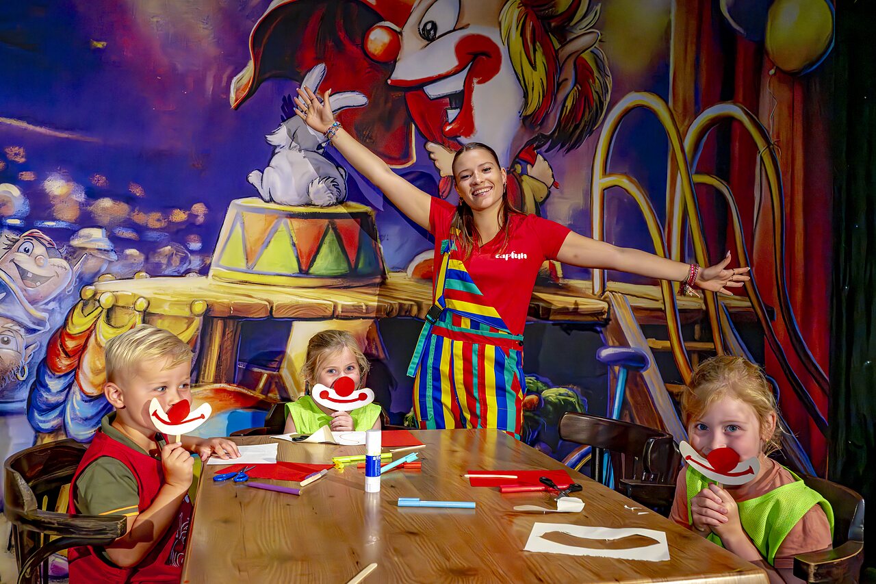 Kinder basteln Clownmasken mit der Animateurin auf dem Campingplatz CAPFUN de Wondermolen in Molenschot.