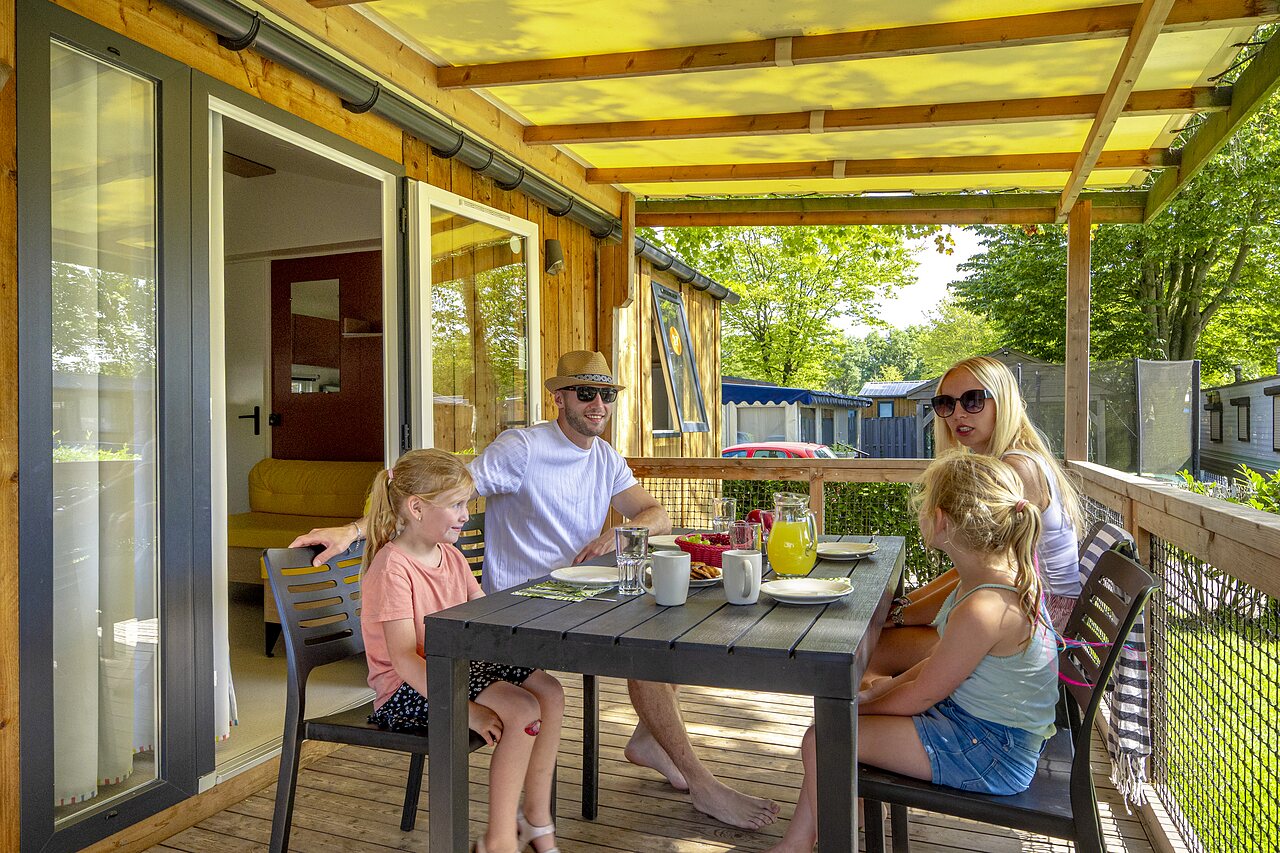 Familie fr�hst�ckt auf Terrasse eines Mobilheims auf Camping CAPFUN de Wondermolen in Molenschot.