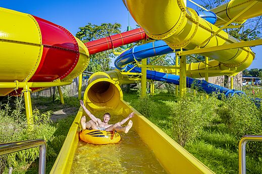 Mann auf Reifen in gelber Wasserrutsche auf dem Campingplatz CAPFUN de Wondermolen in Molenschot.