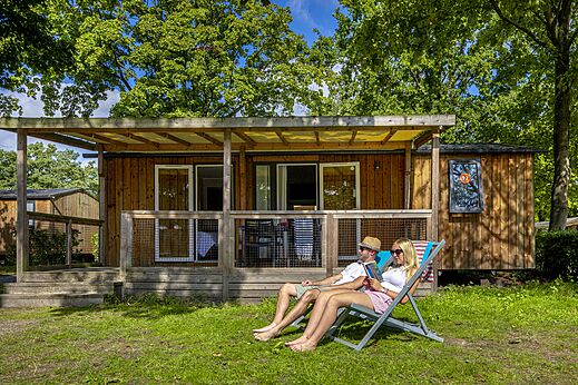 Paar entspannt vor einem Mobilheim mit Terrasse auf dem Campingplatz CAPFUN de Wondermolen in Molenschot.