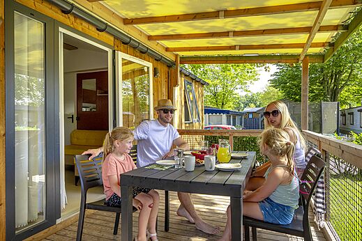 Familie fr�hst�ckt auf der �berdachten Terrasse eines Mobilheims auf dem Campingplatz CAPFUN de Wondermolen in Molenschot.