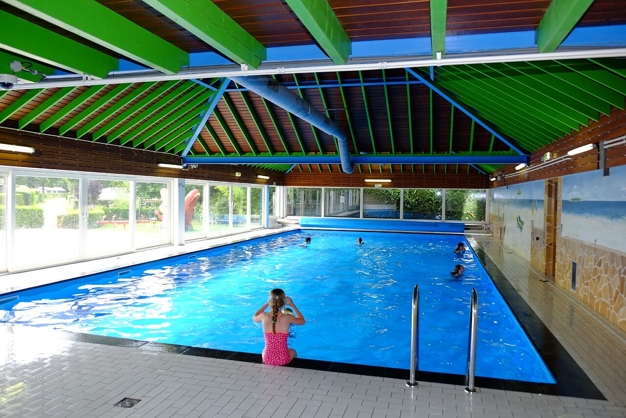 �berdachtes Schwimmbad mit Kindern beim Schwimmen und Spielen auf Camping CAPFUN Zeumersehof in Voorthuizen.