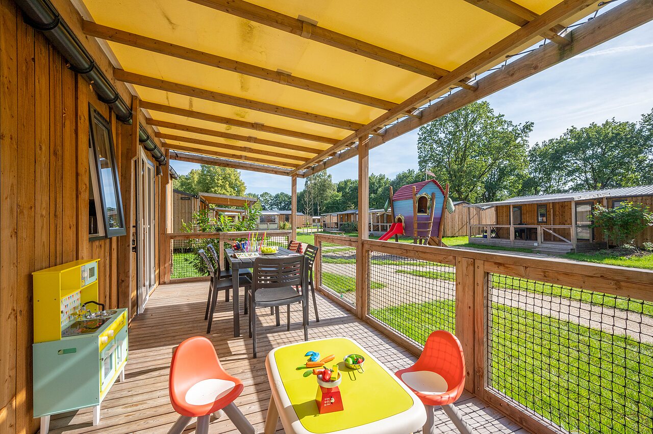 Mobilheim-Terrasse mit Esstisch und Kinderspielen auf dem Campingplatz CAPFUN Zeumersehof in Voorthuizen.