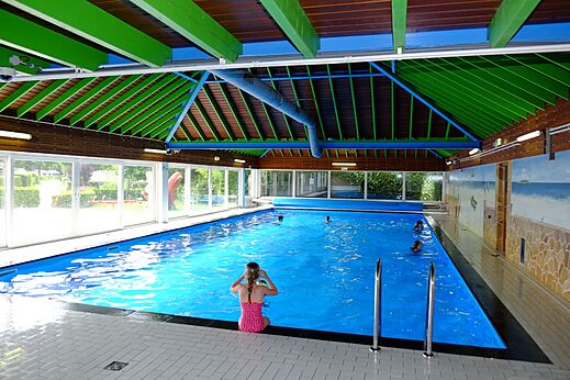 Überdachtes Hallenbad mit Badegästen auf dem Campingplatz CAPFUN Zeumersehof in Voorthuizen.